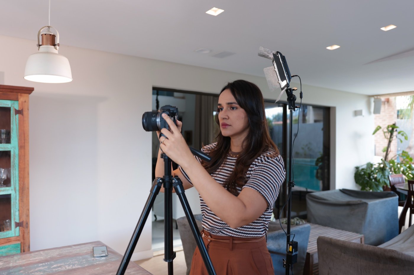 Izabel montando seu setup de gravação com câmera e iluminação profissional